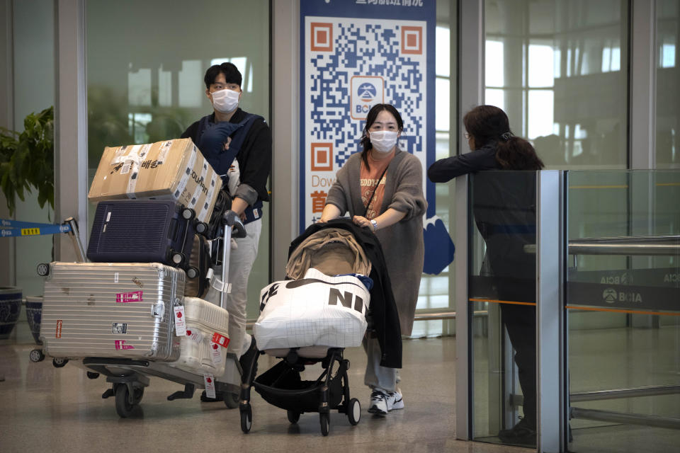 Travelers wearing face masks walk through the international flight arrivals area at Beijing Capital International Airport in Beijing, Wednesday, April 26, 2023. Travelers entering China will no longer need to provide a negative PCR test result starting from Saturday, in another easing of China's "zero-COVID" policies. (AP Photo/Mark Schiefelbein)