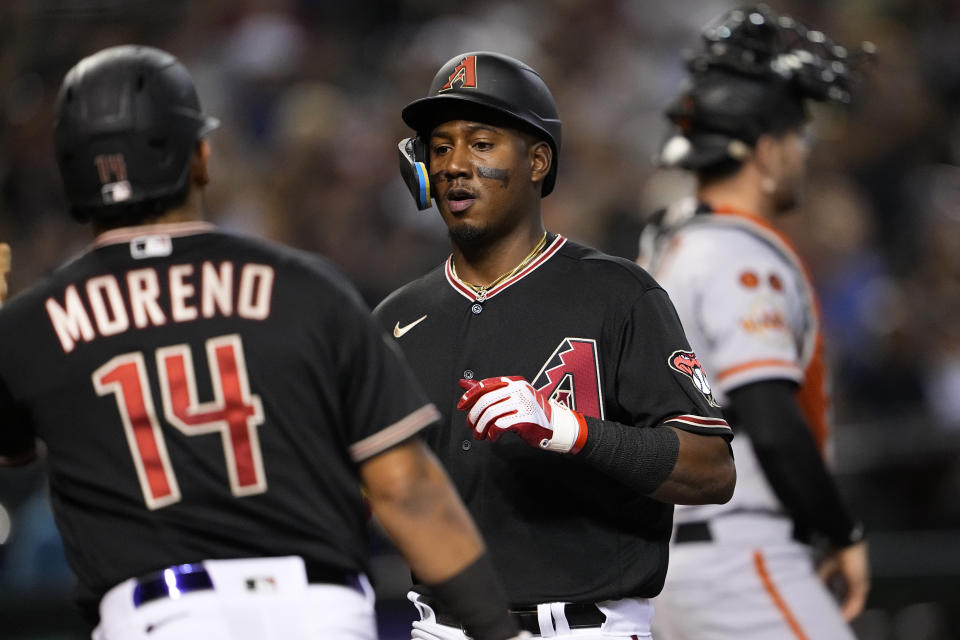 Arizona Diamondbacks' Geraldo Perdomo and Gabriel Moreno (14) celebrate scoring on a double hit by Corbin Carroll during the second inning of a baseball game against the San Francisco Giants, Tuesday, Sept. 19, 2023, in Phoenix. (AP Photo/Matt York)