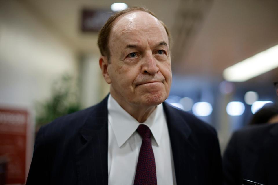 Republican Sen. Richard Shelby of Alabama, his lips pursed, walks through a crowd of reporters as he arrives at the Capitol for a vote on January 31, 2022 in Washington, DC.