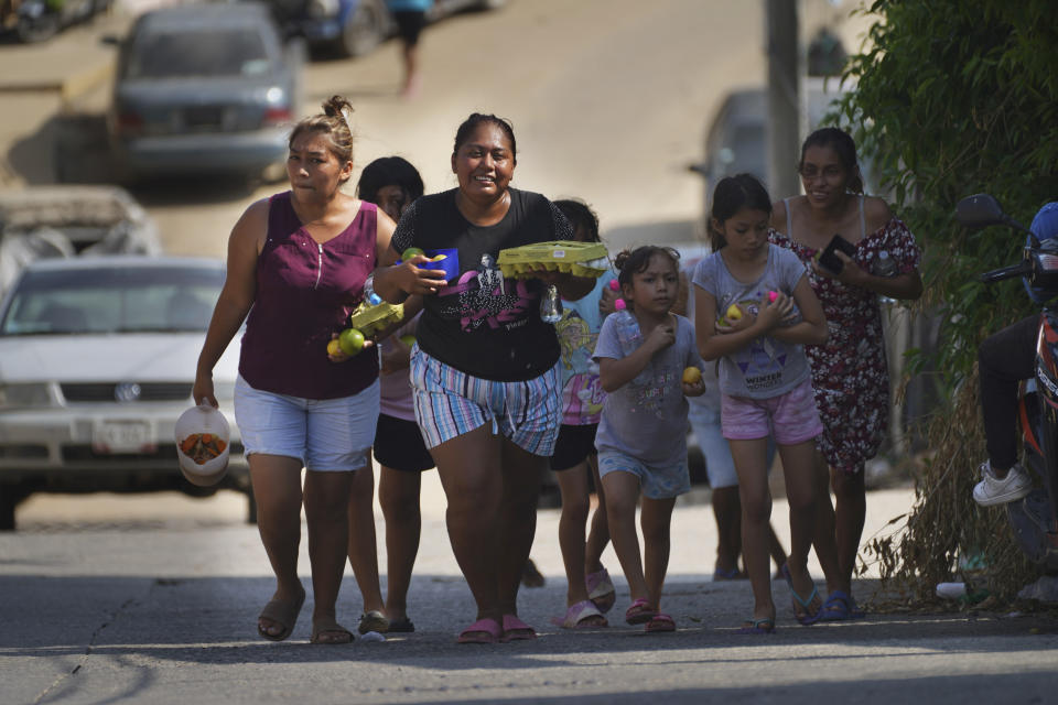 Residentes de regreso a su casa con comida donada tras la devastación que dejó el paso del huracán Otis, en Acapulco, México, el sábado 11 de noviembre de 2023. (AP Foto/Marco Ugarte)