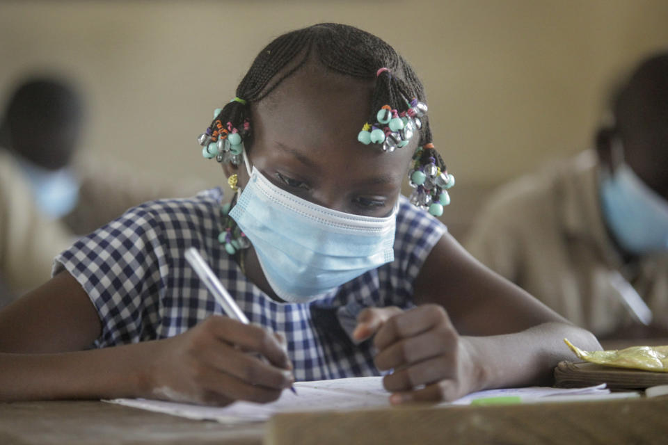 FILE - In this May 25, 2020, file photo, a student wears a mask as she attends a class at a school in the Koumassi neighborhood of Abidjan, Ivory Coast. The options for African students eager to keep studying while schools remain closed because of the coronavirus pandemic seems varied, but the reality for many is that they will fall behind and possibly drop out of school forever, worsening inequality on an already unequal continent. (AP Photo/Diomande Ble Blonde, File)