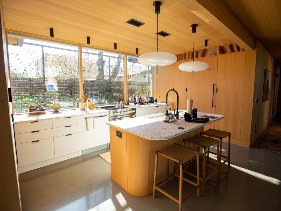 Inside Icon's over 2,000-square-foot House Zero in Austin. There's a kitchen with an island, chairs, in front of large windows that flood the space with light.