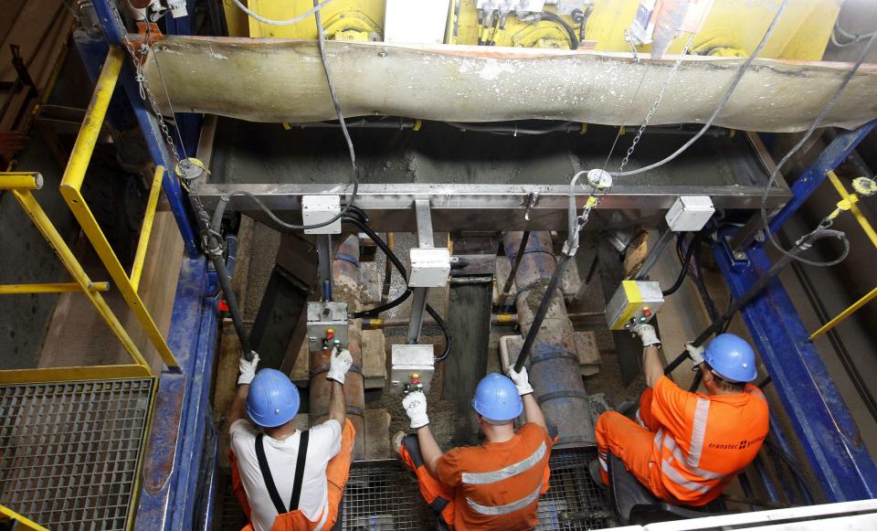 Workers sitting on the special train 'Helvetia' distribute fresh concrete on the track bed of the rails in the NEAT Gotthard Base tunnel near Erstfeld May 7, 2012. The train, which is 481 metres (1578 ft) long and weighs 787 tons, is constructed to produce concrete for the installation of the railway tracks in the tunnel. Crossing the Alps, the world's longest train tunnel should become operational at the end of 2016. The project consists of two parallel single track tunnels, each of a length of 57 km (35 miles )