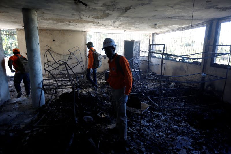 Civil protection workers stand inside a bedroom at an orphanage after it was destroyed in a fire, in Port-au-Prince