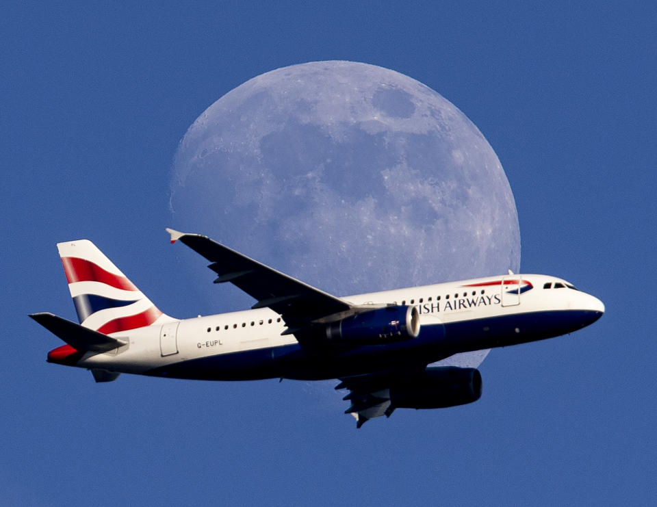 The moon rises as a British Airways aircraft flies on its way to the airport in Frankfurt, Germany, Thursday, June 13, 2019. (AP Photo/Michael Probst)