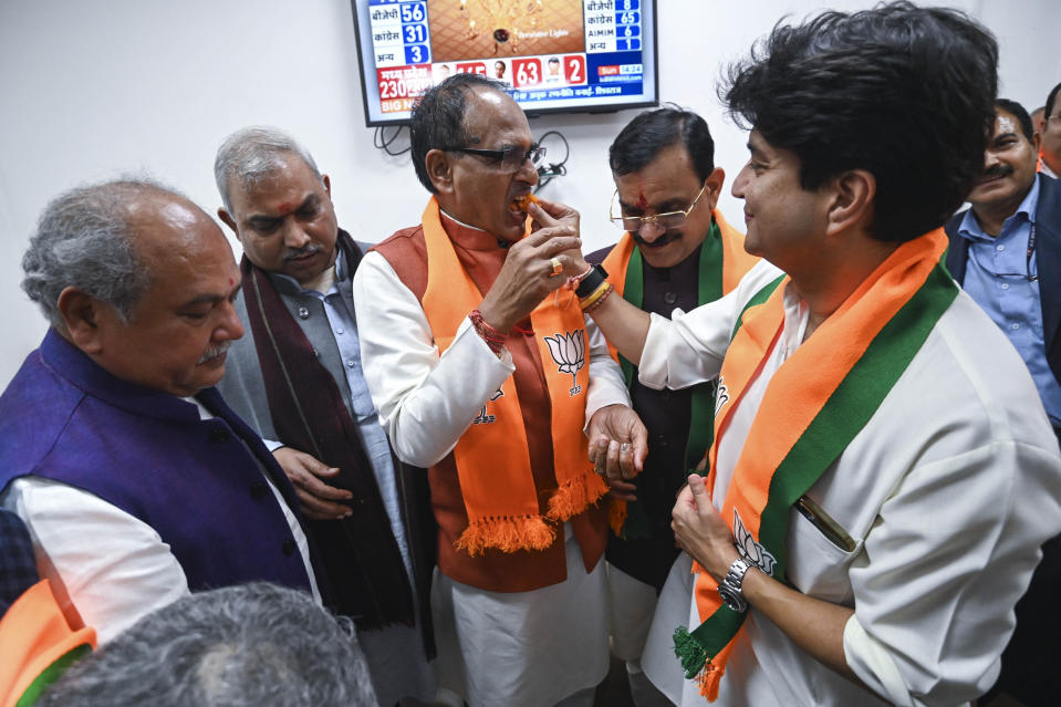 Bharatiya Janata Party (BJP) leader and federal minister Jyotiraditya Scindia, right, offers a sweet to Chief Minister Shivraj Singh Chouhan, center, following BJP's lead in the Madhya Pradesh state elections in Bhopal, India, Sunday, Dec.3 2023. (AP Photo/Abdul Mujeeb Faruqui)