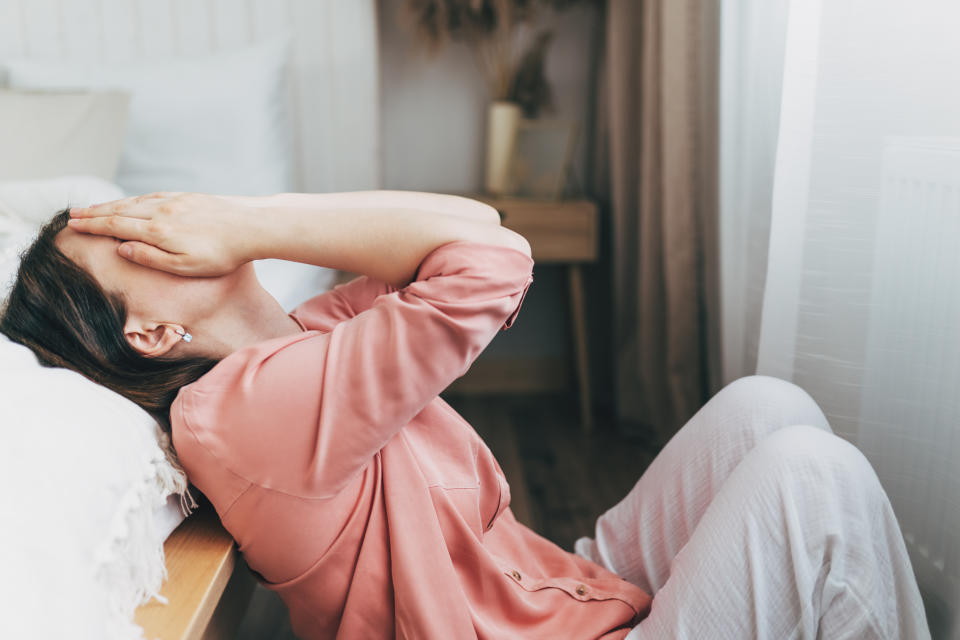 Depressed woman read message from ex-boyfriend lying on sofa covered with blanket together with dog. Anxious female of middle age deleting photos of ex husband from mobile phone crying on couch alone