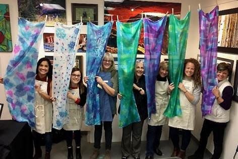 Members of a silk scarf class show off their final products at Blue Moose Art Gallery in Fort Collins. The Midtown gallery hosts 20 art classes a month.