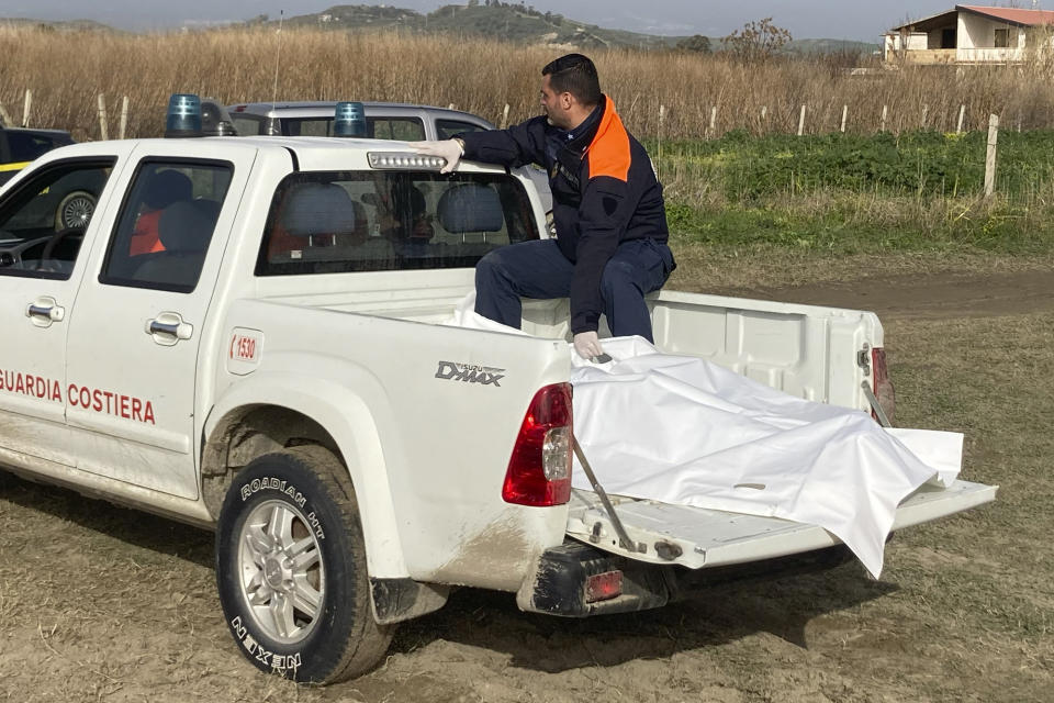 Italian Coast Guard officer sits on a vehicle with the body of a victim of a migrant boat that capsized in rough seas, in Cutro, southern Italy, Tuesday, Feb. 28, 2023. Rescue crews searched by sea and air for the dozens of people believed still missing from a shipwreck off Italy's southern coast that drove home once again the desperate and dangerous crossings of migrants seeking to reach Europe. (AP Photo/Paolo Santalucia)