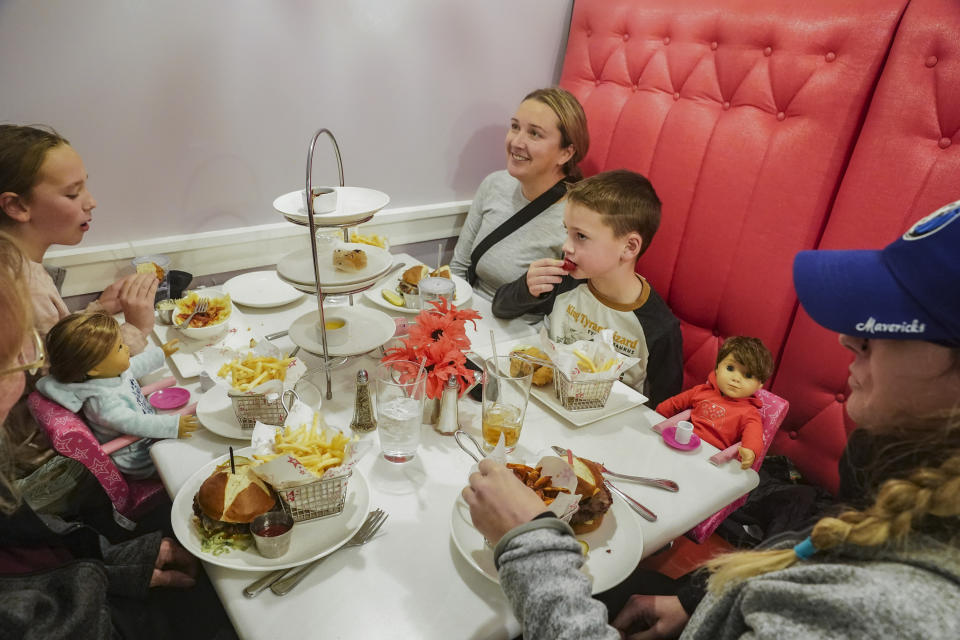 Elizabeth Hulanick, far right, sit with her sister Sara Gaskill, second from left, and her children Abbey, 9, far left, and Jack, 7, second from right, for a meal at the American Girl Cafe, Friday, Dec. 2, 2022, in New York. Hulanick, a 37-year-old Piscataway, New Jersey resident, said she keeps her American Girl doll called Samantha in her China cabinet as a reminder to always be patient.(AP Photo/Bebeto Matthews)