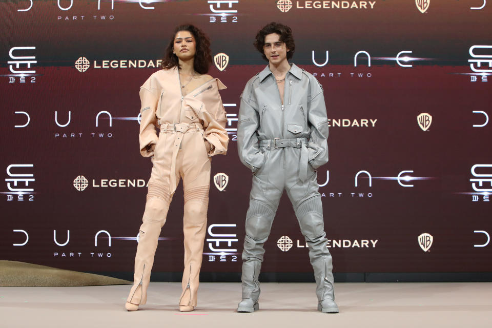 Zendaya and Timothee Chalamet pose in jumpsuits at a press conference for their movie.