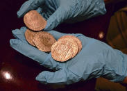 A member of the Ministry technical crew displays some of the 594,000 coins and other artifacts found in the Nuestra Senora de las Mercedes, a Spanish galleon sunk by British warships in the Atlantic while sailing back from South America in 1804, in a warehouse in Tampa, Fla. A 17-ton trove of silver coins recovered from the Spanish galleon was flown Friday Feb. 24, 2012 from the United States to Spain, concluding a nearly five-year legal struggle with Odyssey Marine Exploration, the Florida deep-sea explorers who found and recovered it. (AP Photo/Spain's Culture Ministry, HO)