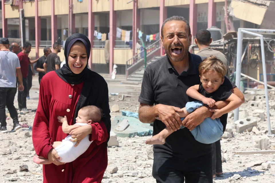 Palestinians carry their children as they flee after an Israeli strike on a school housing displaced people in the Rimal neighborhood of central Gaza City, Aug. 20, 2024, amid the ongoing conflict between Israel and the militant Hamas group. / Credit: OMAR AL-QATTAA/AFP/Getty