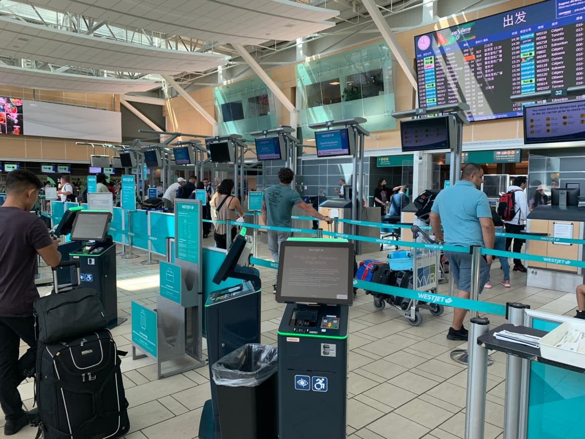 Travellers stand in line to book Westjet flights at the Vancouver International Airport on Friday, May 19, 2023, hours after a labour dispute between pilots and the company was resolved. (Zahra Premji/CBC News - image credit)