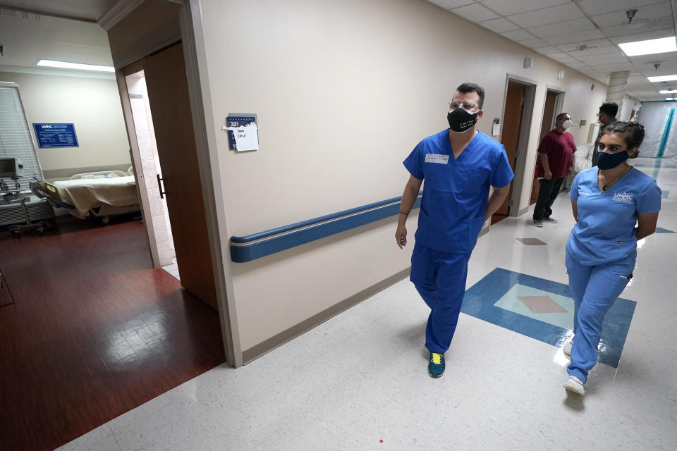 FILE - In this July 16, 2020 file photo, Infectious Disease Physician Army Maj. Gadiel Alvarado, left, with the Urban Augmentation Medical Task Force, walks down the hall with United Memorial Medical Center's Mariya Mohiuddin, director of COVID-19 testing and logistics, inside a newly setup wing in the hospital in Houston. Texas reported a new daily record for virus deaths Friday and more than 10,000 confirmed cases for the fourth consecutive day. (AP Photo/David J. Phillip)