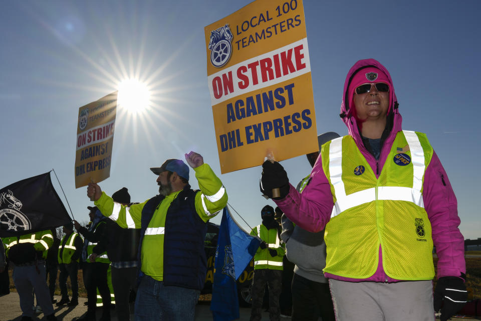 Jessica Taylor, right, and Nick Rutherford, left, protest at Cincinnati/Northern Kentucky International Airport near the DHL Express Hub Friday, Dec. 8, 2023, in Erlanger, Ky. More than 1,000 union members at DHL walked off the job at Cincinnati/Northern Kentucky International Airport, a critical logistics hub for the package delivery company, during the busiest time of the year. The Teamsters say they are protesting unfair labor practices at the DHL Express hub. (AP Photo/Carolyn Kaster)