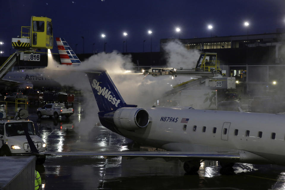 A deicing agent is applied to a SkyWest airplane before its takeoff, Friday, Jan. 18, 2019, at O'Hare International Airport in Chicago. The National Weather Service issued winter storm warnings from the Dakotas, across the Great Lakes states and into New England. The weather service at one point warned that conditions in New England over the weekend "could approach blizzard criteria." Ice was also a possibility in some areas in the storm's path. (AP Photo/Kiichiro Sato)