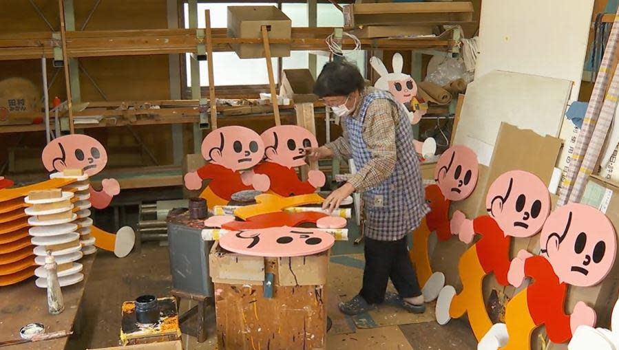 A woman works in a shop in Higashi-Omi, Japan, making the ubiquitous Running Boy signs that dot the roads throughout the city, and the country. / Credit: CBS News