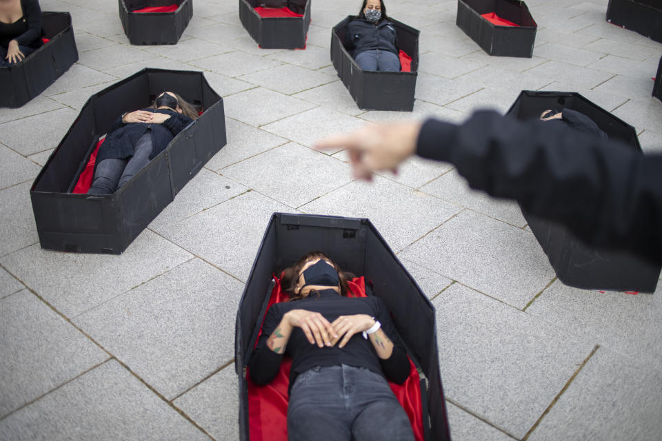 Women laying in coffins representing women killed in domestic violence during an event for upcoming International Women's Day in front of Tel Aviv's district court, Israel, Sunday, March 7, 2021. (AP Photo/Ariel Schalit)