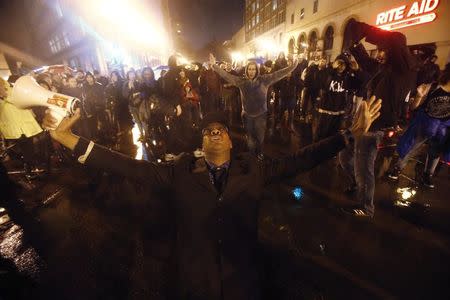 David Scott, of Oakland, kneels with his hands raised during a demonstration against the New York City grand jury decision to not indict in the death of Eric Garner in Oakland, California December 3, 2014. REUTERS/Stephen Lam