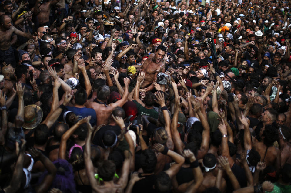 In this photo taken on Friday, Sept. 6, 2019, people painted with black grease celebrate during the traditional festivities of the Cascamorras festival in Baza, Spain. During the Cascamorras Festival, and according to an ancient tradition, participants throw black paint over each other for several hours every September 6 in the small town of Baza, in the southern province of Granada. The "Cascamorras" represents a thief who attempted to steal a religious image from a local church. People try to stop him, chasing him and throwing black paint as they run through the streets. (AP Photo/Manu Fernandez)