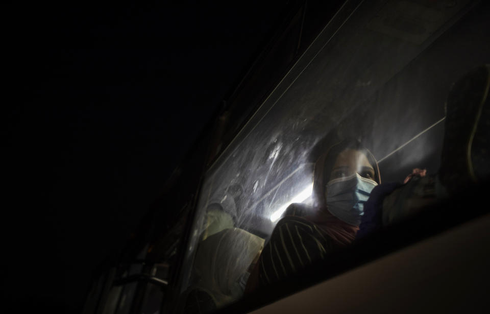 A Palestinian woman wearing a face mask to prevent the spread of the coronavirus waits in a bus in Gaza City to go to the Rafah border crossing into Egypt on Sept. 27, 2020. (AP Photo/Khalil Hamra)