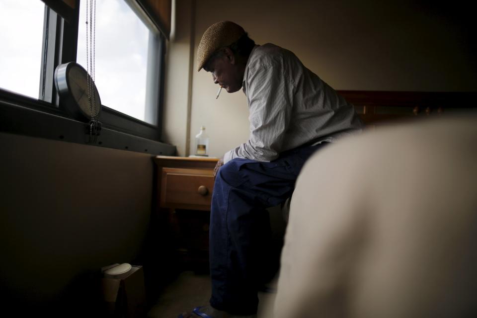 Errol Morning, a Hurricane Katrina survivor, sits on his bed as he smokes a cigarette at his apartment in New Orleans, Louisiana, August 15, 2015. (REUTERS/Carlos Barria)