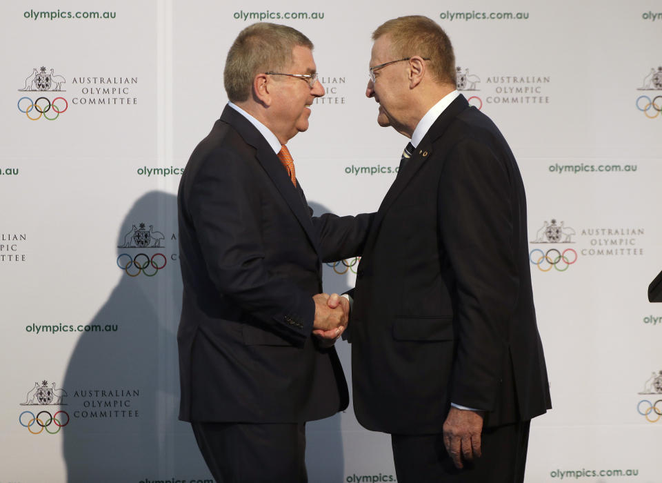 FILE - In this Saturday, May 4, 2019 file photo, International Olympic Committee President Thomas Bach, left, shakes hands with Australian Olympic Committee (AOC) President John Coates at the AOC annual general meeting in Sydney, Australia. The Australian Olympic bid is on a fast-track to host the 2032 Olympics Wednesday Feb. 24, 2021, after the International Olympic Committee executive board gave Queensland “preferred bidder” status, 11 years ahead of the games.(AP Photo/Rick Rycroft, File)