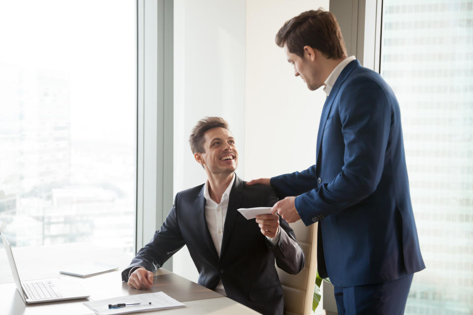 General manager presenting an envelope with premium or bonus cash to male company official. Boss congratulating happy employee with career promotion, thanking for good job and giving financial reward