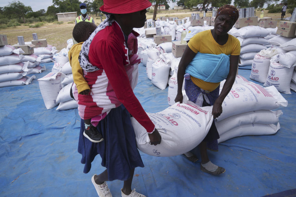 Zanyiwe Ncube, right, carries a bag of sorghum during a food distribution in Mangwe district in southwestern Zimbabwe, Friday, March, 22, 2024. A new drought has left millions facing hunger in southern Africa as they experience the effects of extreme weather that scientists say is becoming more frequent and more damaging. (AP Photo/Tsvangirayi Mukwazhi)