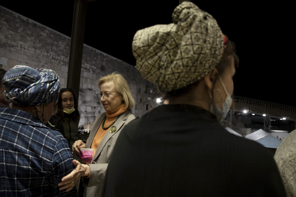 Colette Avital, chair of the Center of Organizations of Holocaust Survivors in Israel, center, speaks with relatives of a Holocaust survivor who recently passed away, during a Hanukkah menorah lighting ceremony at the Western Wall, in the Old City of Jerusalem, Tuesday, Nov. 30, 2021. Holocaust survivors marked the third night of Hanukkah on Tuesday with a menorah-lighting ceremony at Jerusalem's Western Wall that paid tribute to them and the 6 million other Jews who were killed by the Nazis. (AP Photo/Maya Alleruzzo)