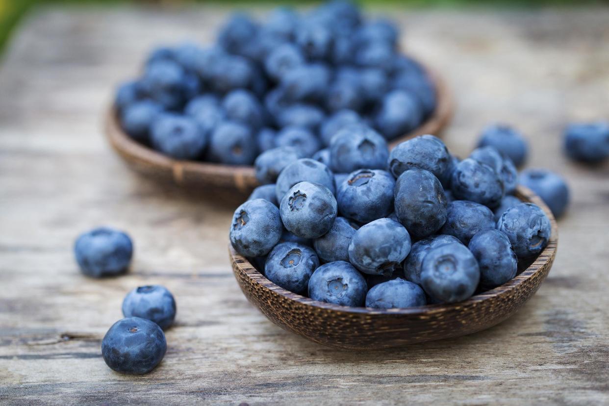 blueberries in wooden bowl and wooden table