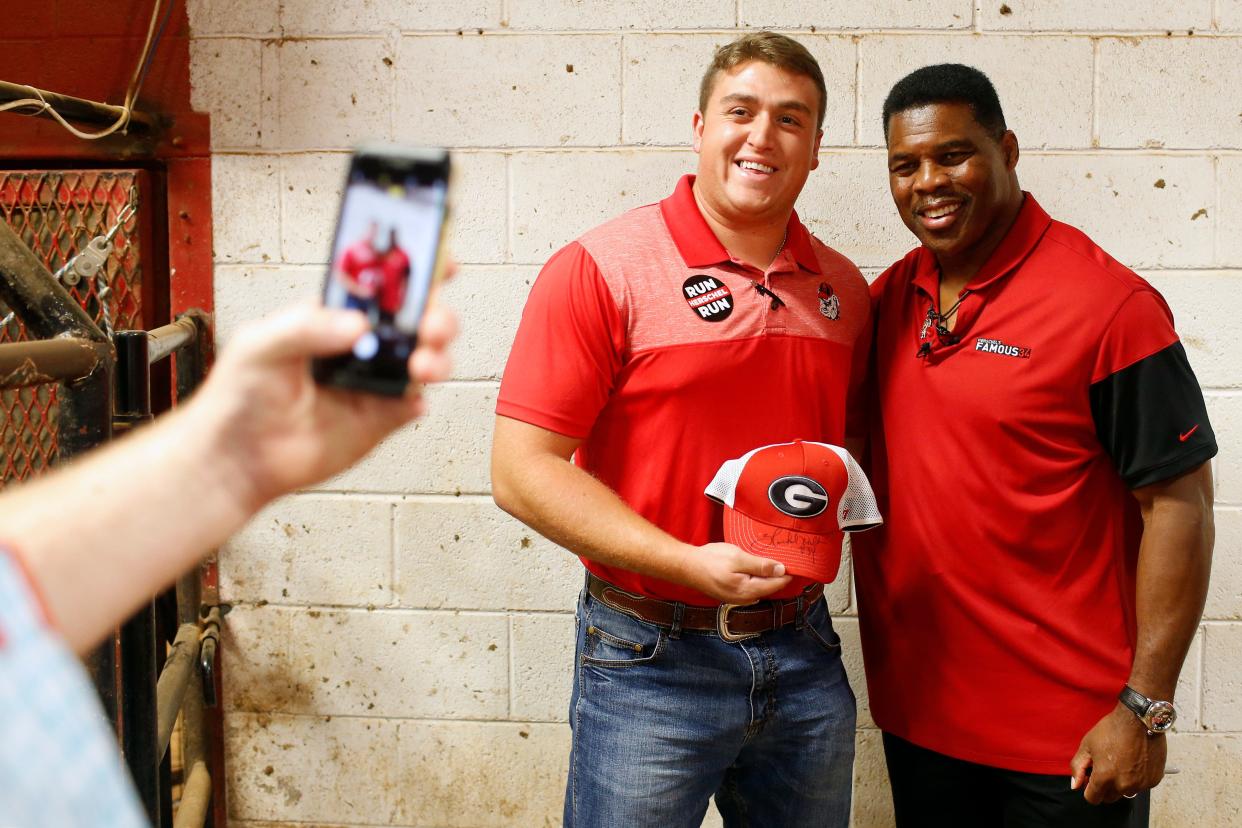 Republican Senate candidate Herschel Walker poses for a photo with a supporter at the Northeast Georgia Livestock Barn in Athens on Wednesday. Walker spoke about gas prices and the November election.