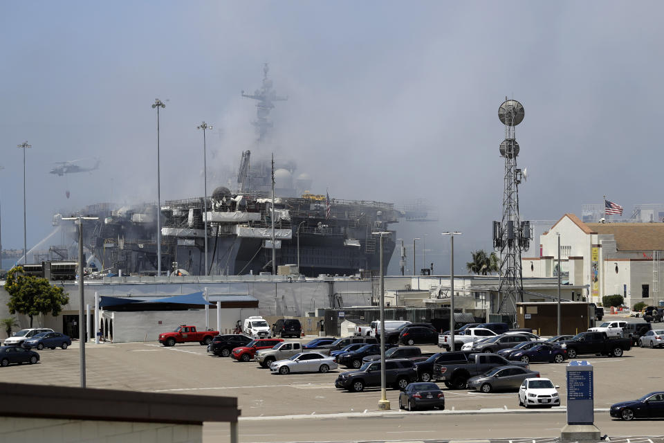 A helicopter drops water on the USS Bonhomme Richard as crews fight the fire Monday, July 13, 2020, in San Diego. Fire crews continue to battle the blaze Monday after 21 people suffered minor injuries in an explosion and fire Sunday on board the USS Bonhomme Richard at Naval Base San Diego. (AP Photo/Gregory Bull)