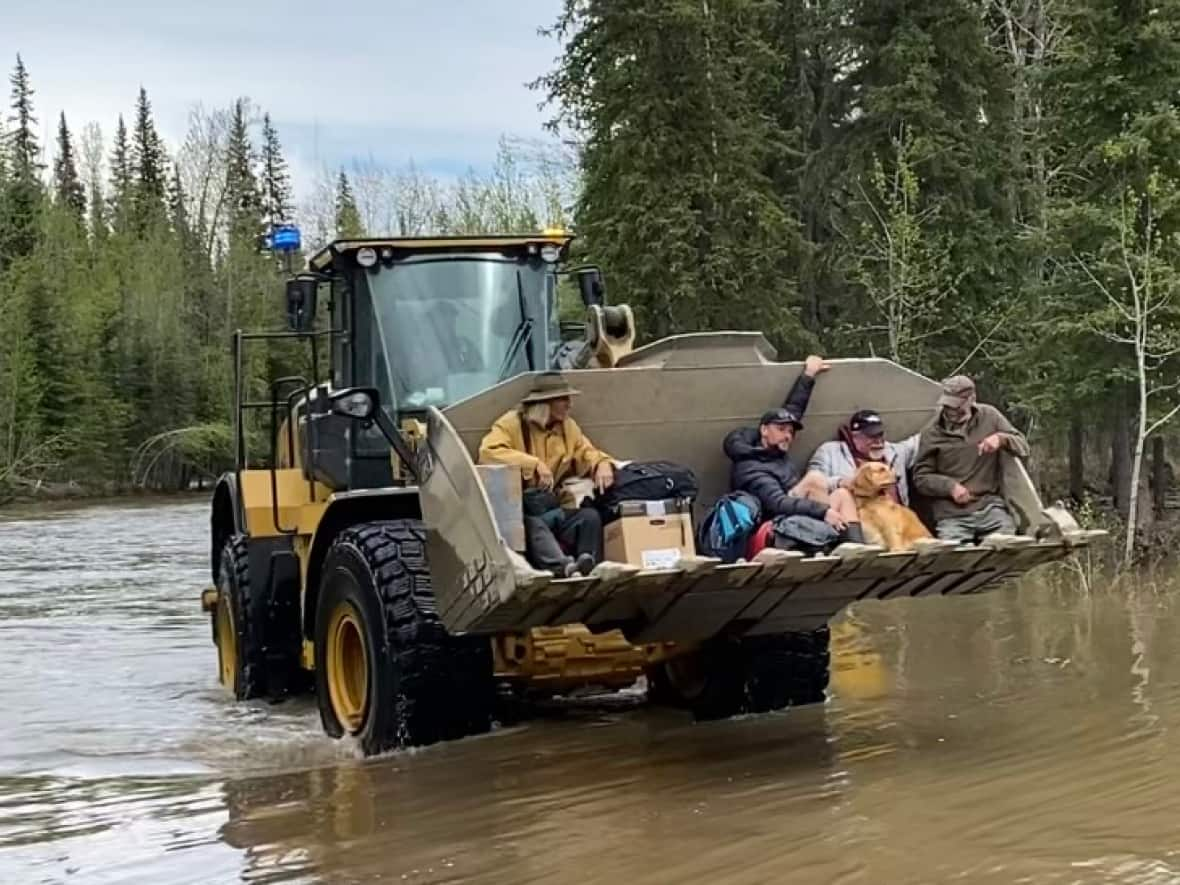 An excavator is used to carry people out of a flooded campground near Dawson City, Yukon, May 24, 2023. (Chris MacIntyre/CBC - image credit)