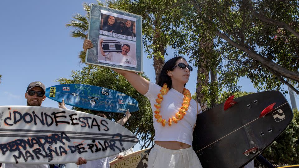 A demonstrator holds photos of the surfers during a protest in Ensenada, Mexico, on May 5, 2024. - Karen Castaneda/AP