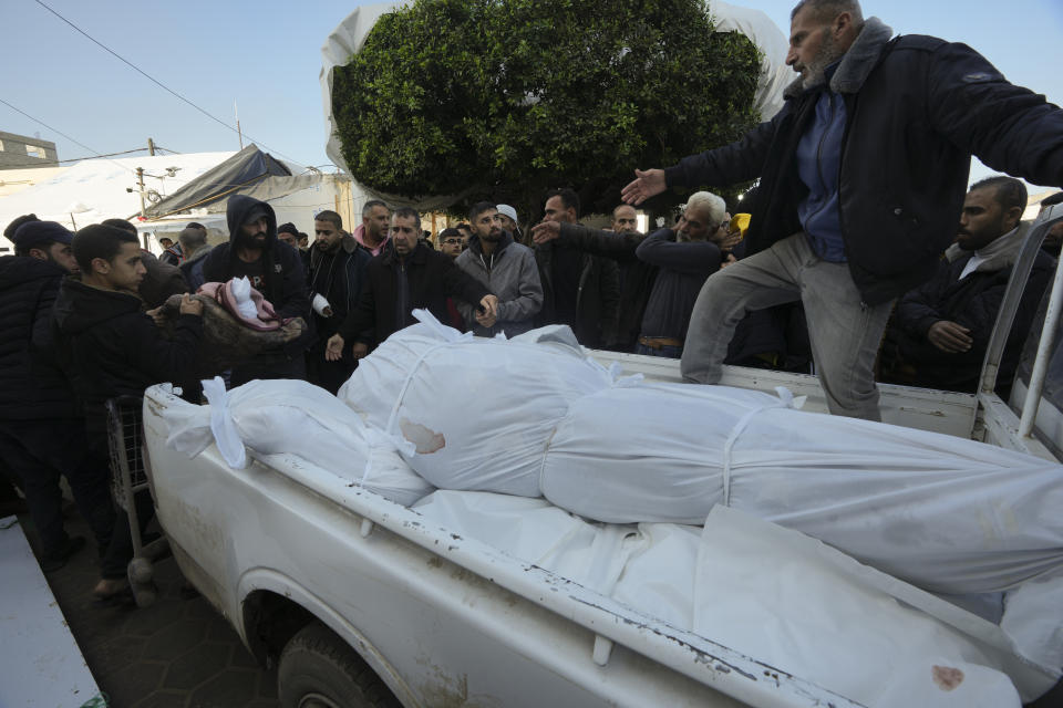 Palestinians load the bodies of their relatives killed in the Israeli bombardment of the Gaza Strip on a truck in Deir al Balah, Gaza Strip, on Tuesday, Jan. 2, 2024. (AP Photo/Adel Hana)