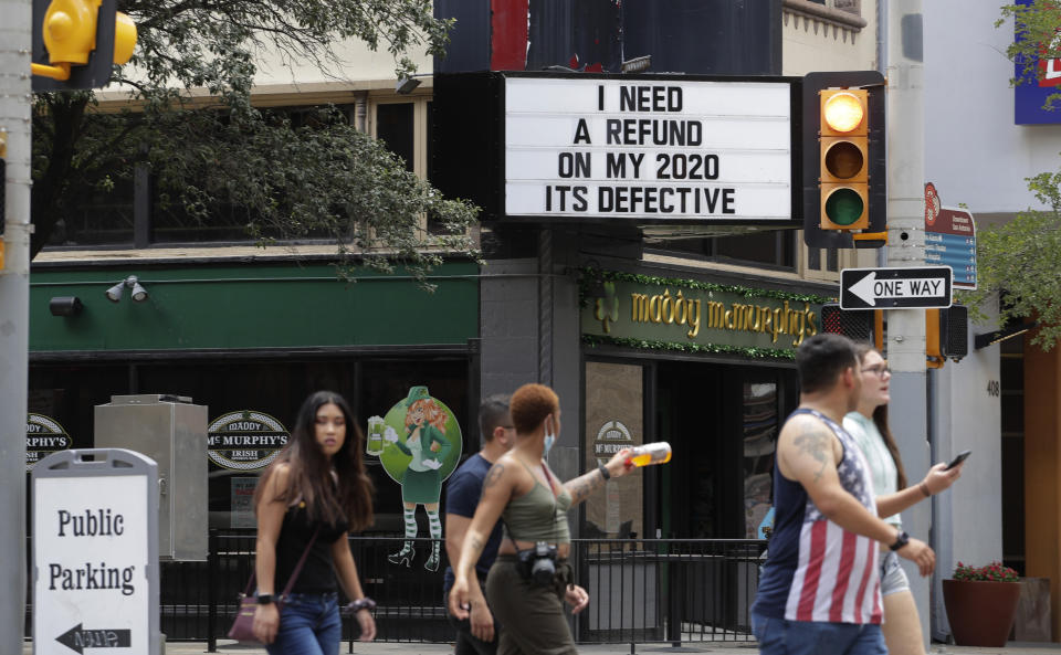 Visitors, some wearing masks to protect against COVID-19, walk through downtown San Antonio, Monday, July 20, 2020. Cases of COVID-19 continue to spike in Texas. (AP Photo/Eric Gay)