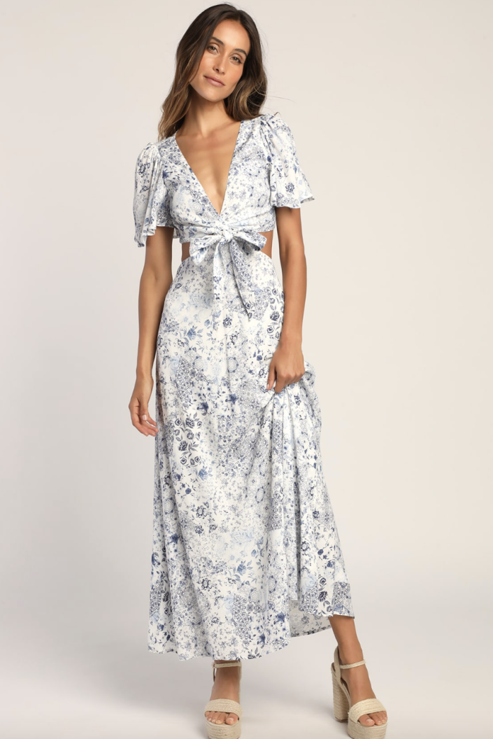 brunette model in white and blue floral Stroll the Avenues White Floral Print Tie-Front Maxi Dress (Photo via Lulus)