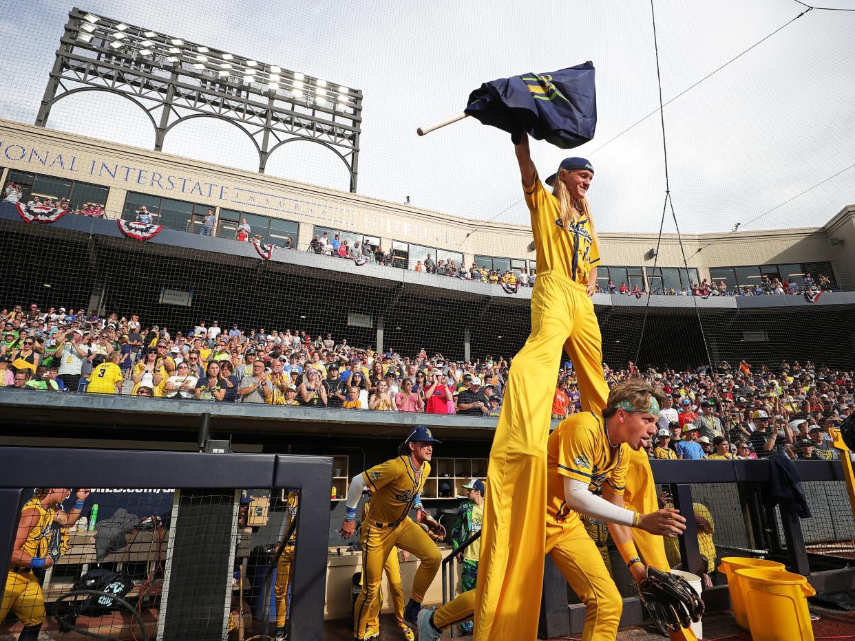 Players rush through the legs of Dakota Albritton, aka Stilts, as they take the field during the pregame announcements before the Savannah Bananas' World Tour at Canal Park, Monday, July 3, 2023, in Akron, Ohio.