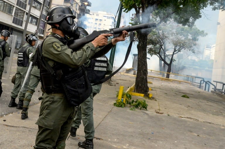 Venezuelan National Guard personnel in riot gear fire tear gas grenades at opposition activists in Caracas on April 10, 2017