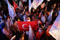 A supporter of the newly elected Turkish Cypriot leader Ersin Tatar holds a Turkish flag and celebrates with others in the Turkish occupied area in the north part of the divided capital Nicosia, Cyprus, Sunday, Oct. 18, 2020. Ersin Tatar, a hardliner who favors even closer ties with Turkey and a tougher stance with rival Greek Cypriots in peace talks has defeated the leftist incumbent in the Turkish Cypriot leadership runoff. (AP Photo/Nedim Enginsoy)