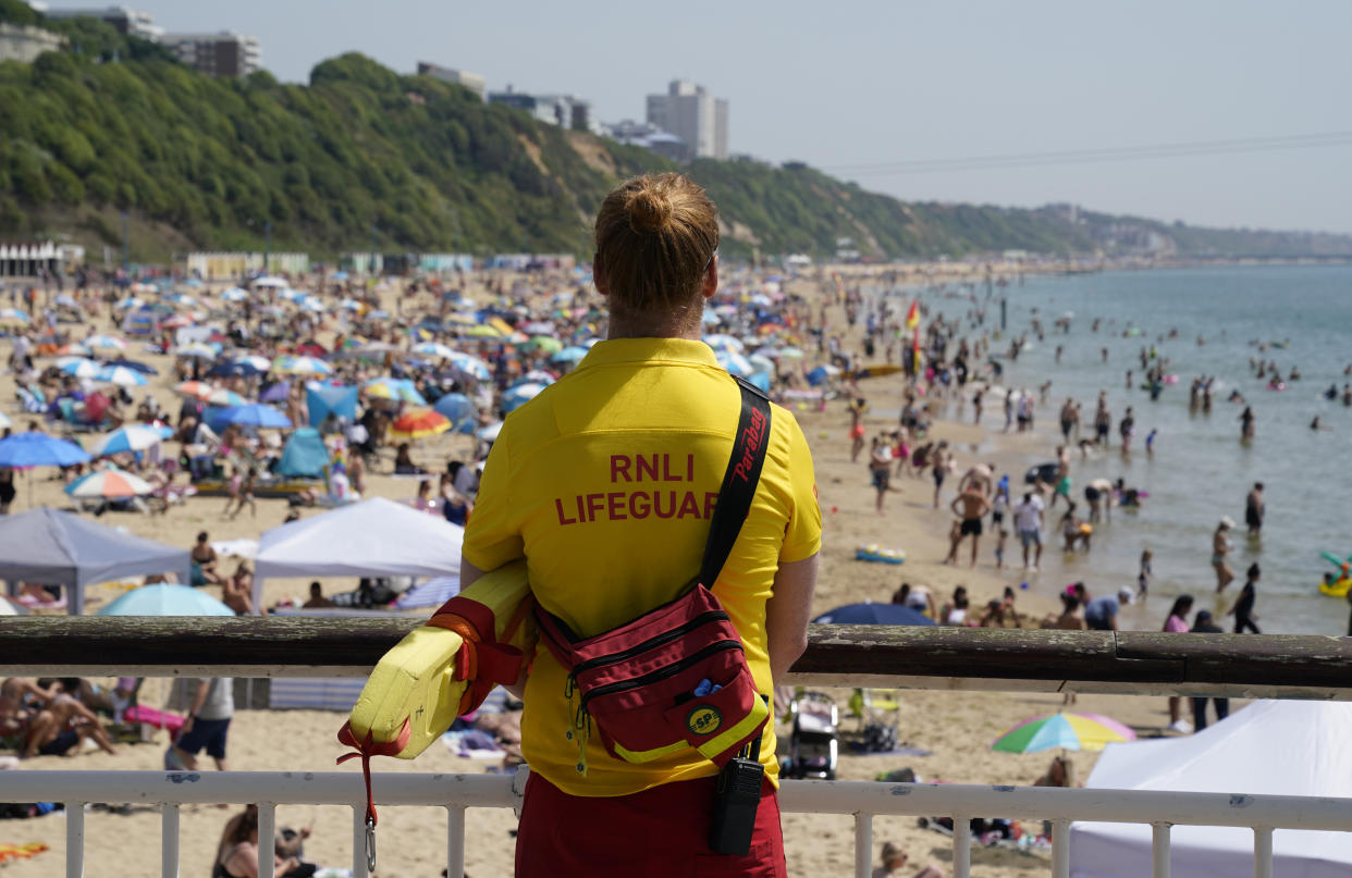 An RNLI Lifeguard overlooks a crowded beach in Dorset