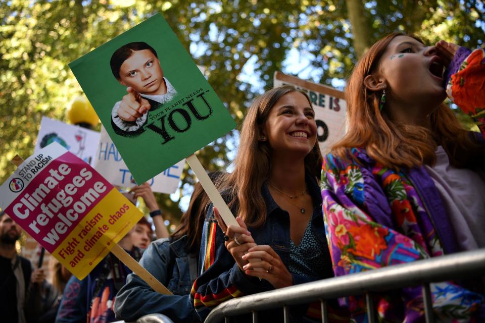 A striker holding a Greta Thunberg–decorated protest sign in London