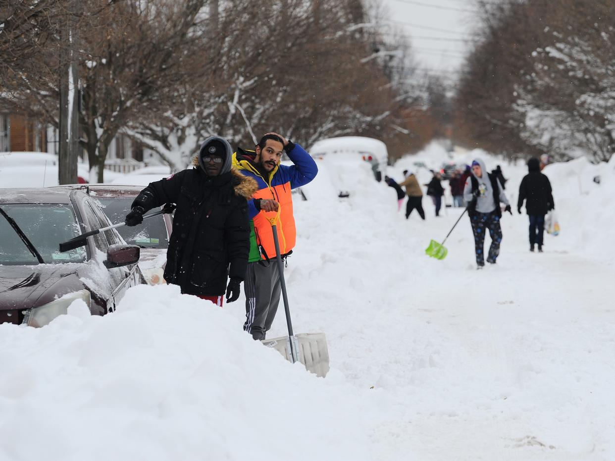 Residents on Woodside Drive clear heavy snow on December 27, 2022 in Buffalo, New York. The historic winter storm Elliott dumped up to four feet of snow, leaving thousands without power and at least 28 confirmed dead in the city of Buffalo and the surrounding suburbs.