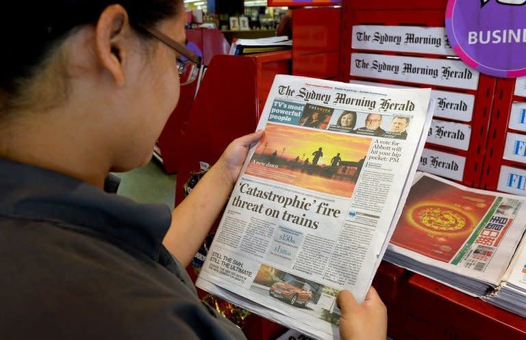 A woman looks at the new tabloid-sized version of The Sydney Morning Herald (SMH) in Sydney on March 4, 2013. Australian broadsheet newspapers SMH and The Age on Monday ditched their century-old format for tabloid in a major overhaul at ailing media giant Fairfax