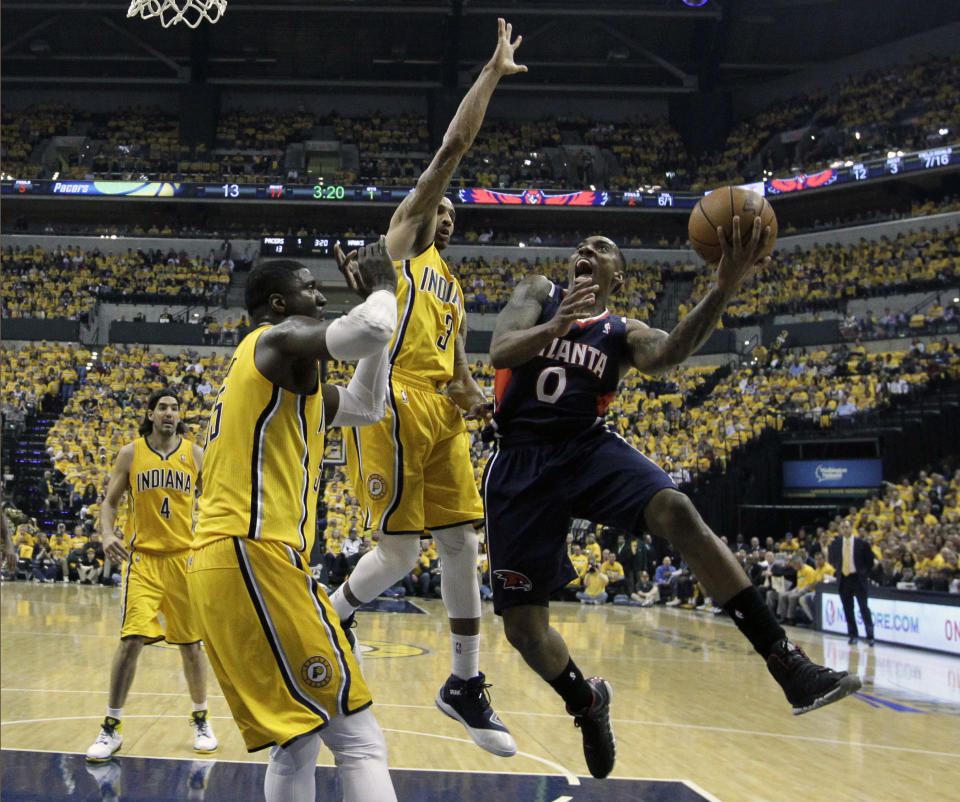 Atlanta Hawks' Jeff Teague shoots against Indiana Pacers' Roy Hibbert and George Hill (3) during the first half in Game 1 of an opening-round NBA basketball playoff series on Saturday, April 19, 2014, in Indianapolis. (AP Photo/Darron Cummings)