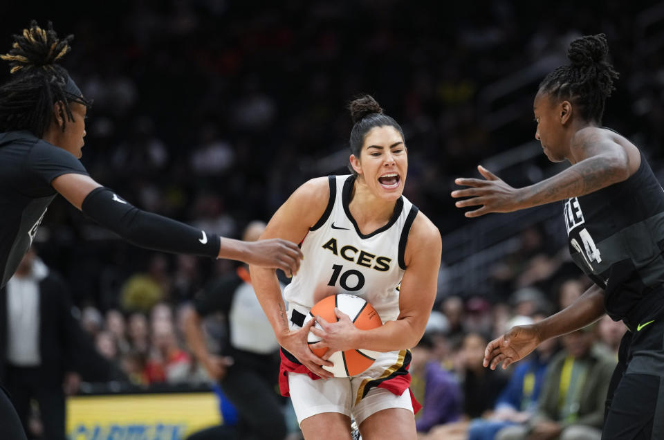 Las Vegas Aces guard Kelsey Plum (10) pushes through the defense of Seattle Storm guards Jordan Horston, left, and Jewell Loyd, right, during the first half of a WNBA basketball game Saturday, May 20, 2023, in Seattle. (AP Photo/Lindsey Wasson)