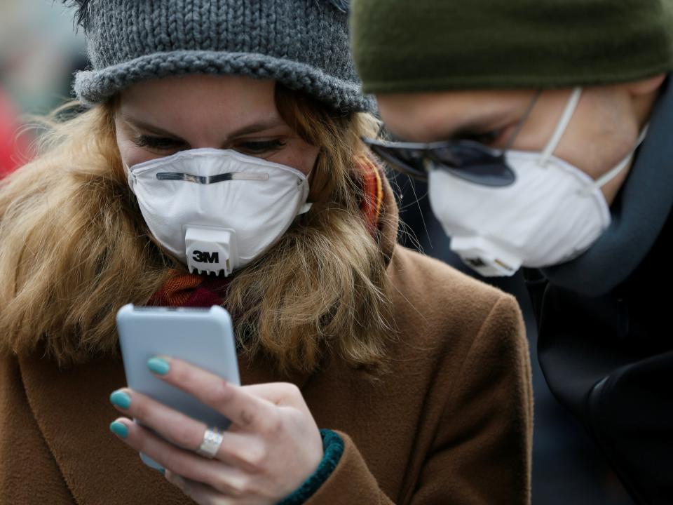 FILE PHOTO: People wearing protective face masks use a smartphone on a street amid coronavirus (COVID-19) concerns in Kiev, Ukraine March 17, 2020.  REUTERS/Valentyn Ogirenko