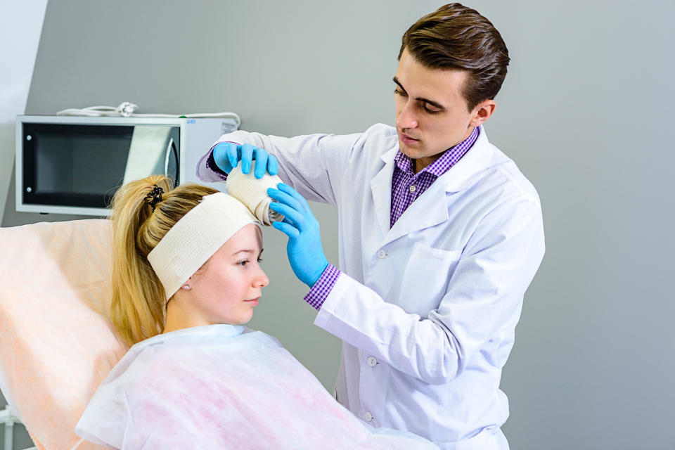 Doctor applying an elastic bandage on the contours of the face for gentle skin recovery after plastic surgery